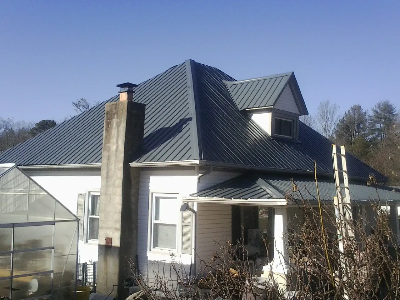 Dark blue standing seam metal roof on a white farmhouse with dormer — Slate & Tile Roof Repair by Roofing Brothers in Franklinville