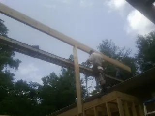 Carpenter setting a ridge beam over a new addition frame — Ice Dam Removal by Roofing Brothers in Franklinville