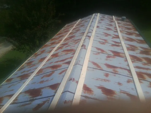 Rusted metal roof panels with new wood purlins before replacement in Franklinville